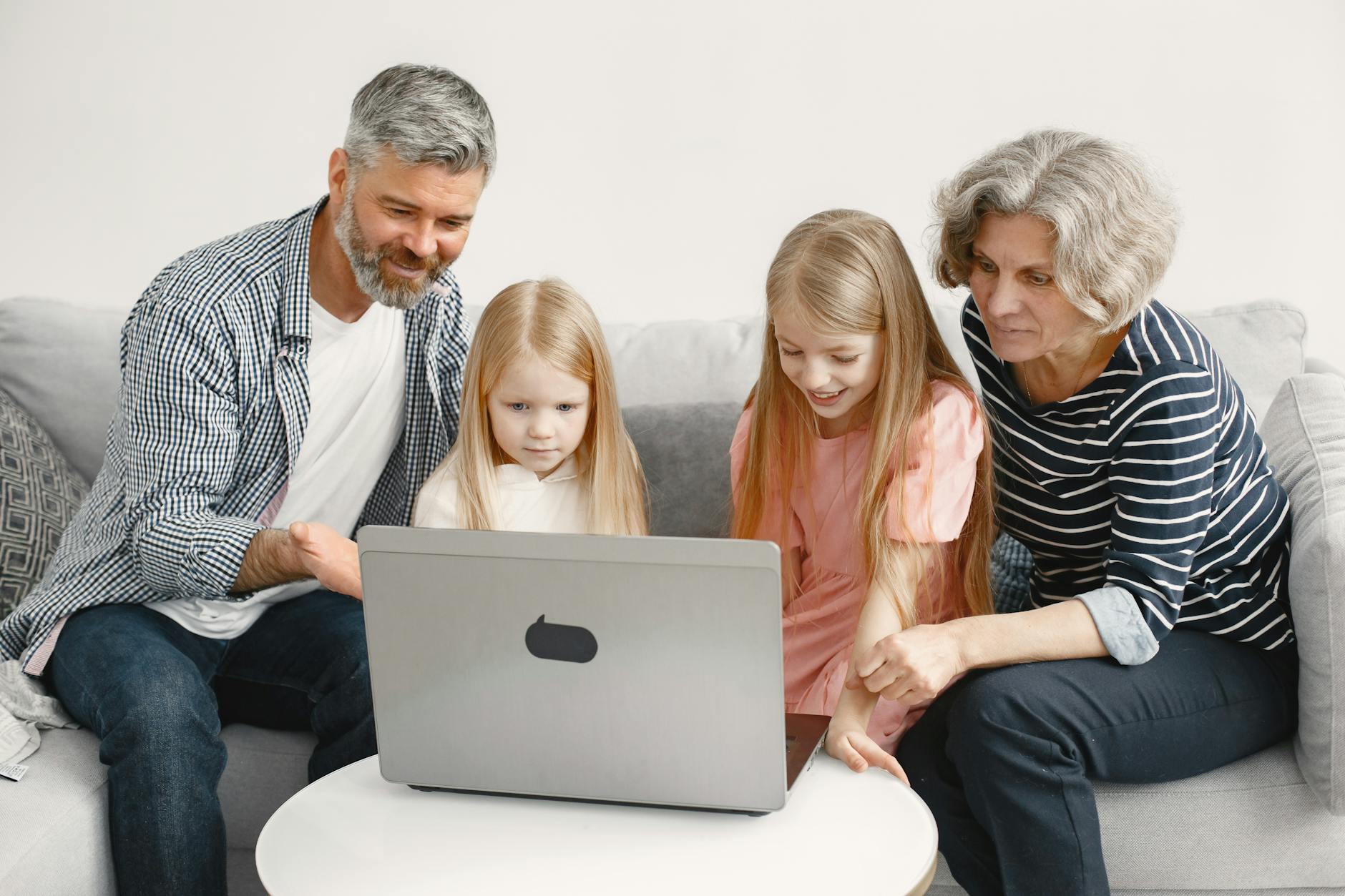 Grandparents enjoying quality time with grandchildren using a laptop at home.